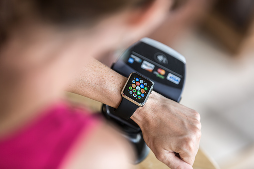 Laval, Сanada - August 25, 2015: Woman Paying at counter using Apple Watch and an electronic reader. The Apple Watch became available April 24, 2015 and is the latest device produced by Apple.