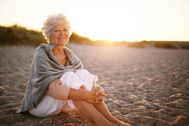 istock Retired woman sitting on the beach 485630245