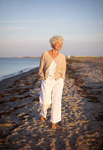 senior femme marchant sur la plage - retirement beach women vacations photos et images de collection