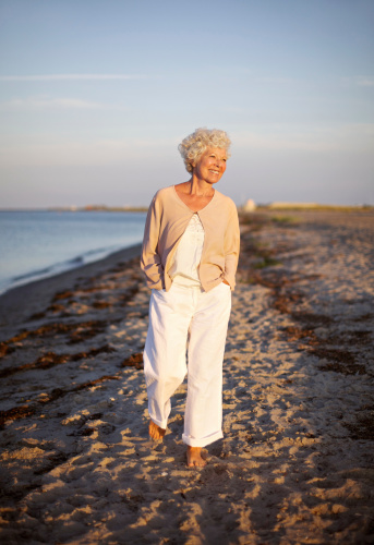 Image of senior woman walking on the beach. Happy and relaxed caucasian female strolling on the beach.