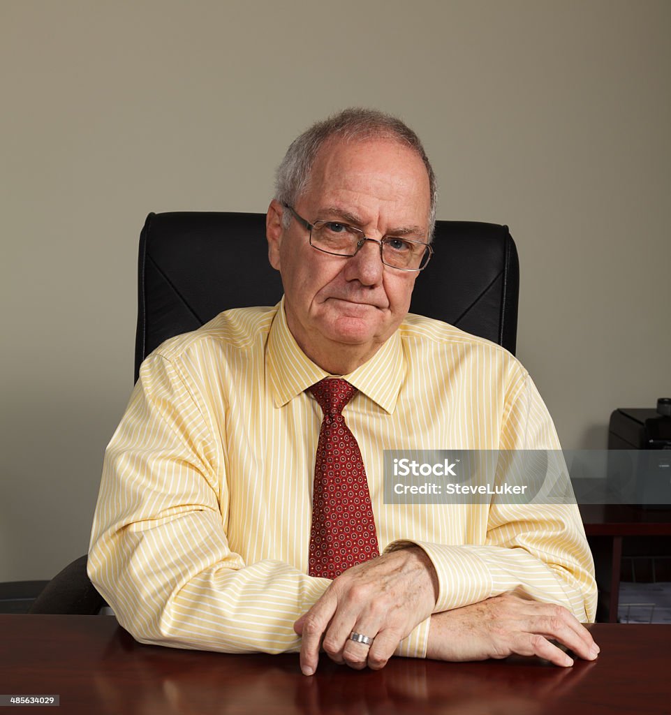 Serious Senior Businessman Businessman sitting at his work desk with an unhappy expression. Businessman Stock Photo