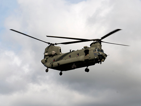 UK military Chinook helicopter in flight with rotor blades almost but not quite frozen by the speed of the shot. 