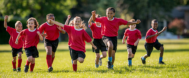 Soccer Players Running and Cheering A multi-ethnic group of elementary age children running across the field cheering victoriously over their winning game. sports activity stock pictures, royalty-free photos & images