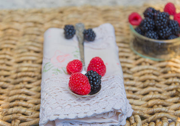 Raspberries and blackberries over lace napkin. stock photo
