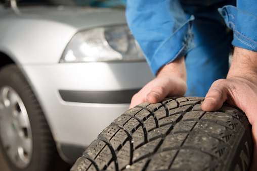 Mechanic's hands holding a car tire.