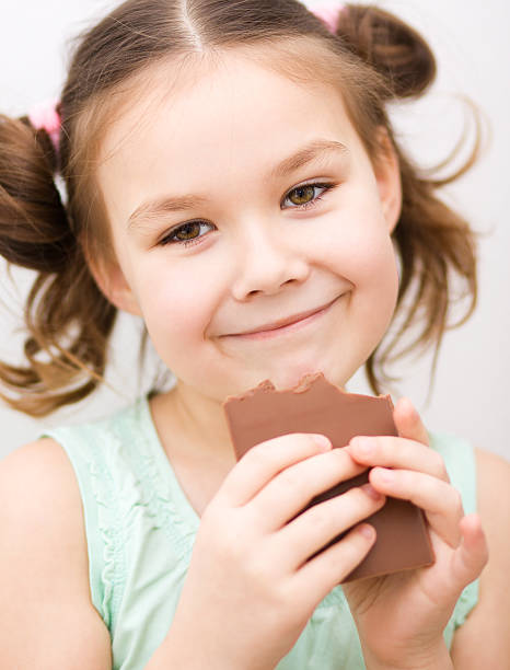 istock Cute girl is eating chocolate candy 485651773