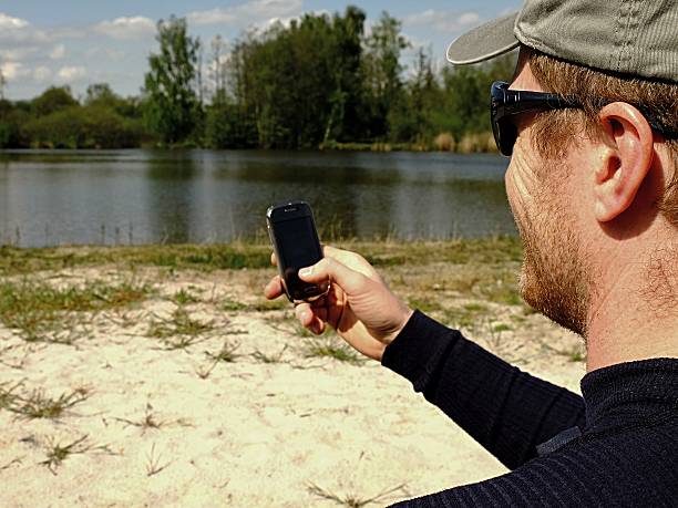 homem na praia com lago e writte no telefone inteligente - writte imagens e fotografias de stock