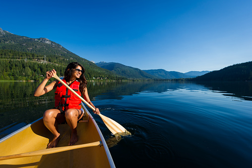 Female paddling a canoe on a prisitine mountain lake