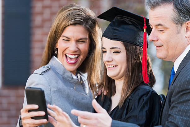 istock Family at graduation looking at mobile phone 485663136
