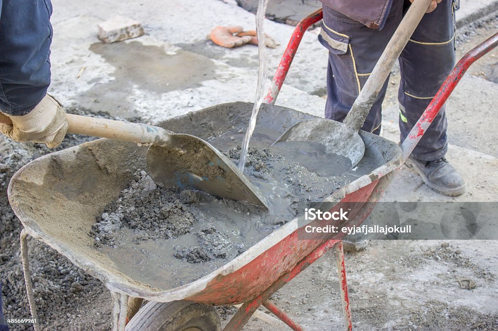 Lavoratori di miscelare il cemento a mano in carriola 3 - Foto stock royalty-free di Acqua