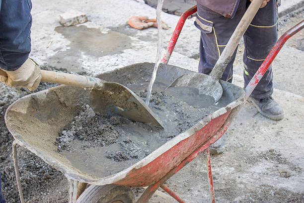 workers mixing the cement by hand in wheelbarrow close up, old fashioned way mixing