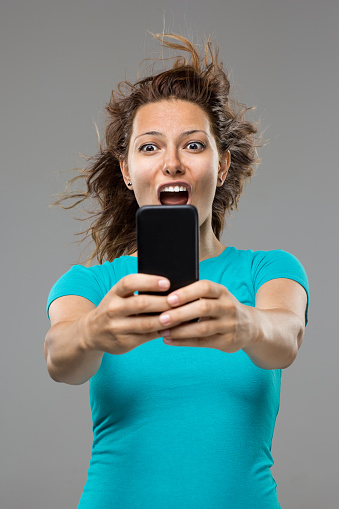 Young woman holding smart phone and screaming