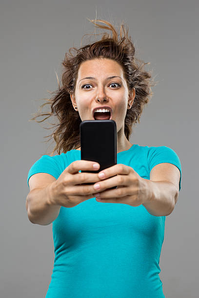 Blowing speed Young woman holding smart phone and screaming windspeed stock pictures, royalty-free photos & images