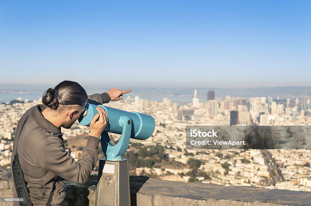 Man watching Francisco Downtown on a binocular from Twin Peaks San Francisco - California Stock Photo
