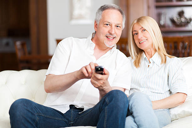 istock Senior couple sitting in couch and watching tv 485673488