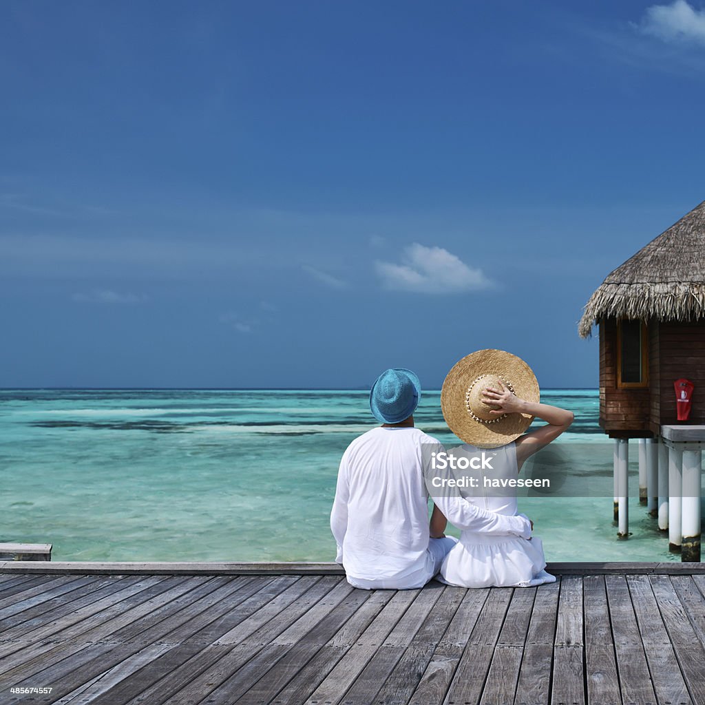 Couple on a beach jetty at Maldives Couple on a tropical beach jetty at Maldives Couple - Relationship Stock Photo