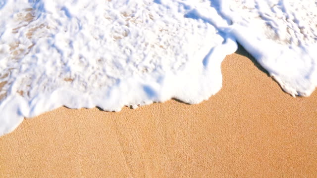 Close Up Shot of Waves Rolling Up White Sand Beach.