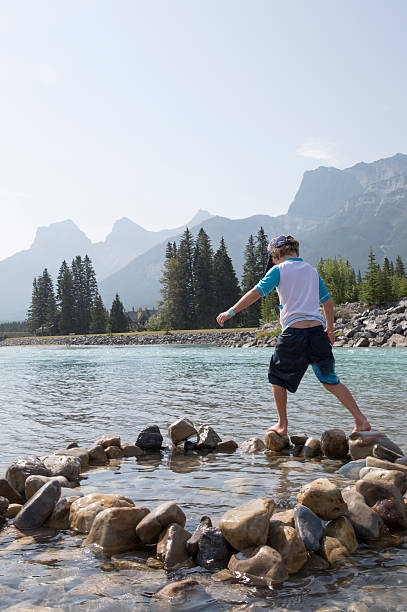 istock Young boy balances on river rock circle, wading 485677480