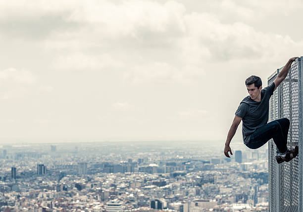 Practicing parkour in the city Urban parkour Man climbing fence free running stock pictures, royalty-free photos & images