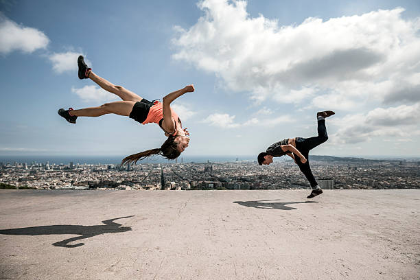 junger mann und frau üben parkour- in der stadt - stuntman stock-fotos und bilder