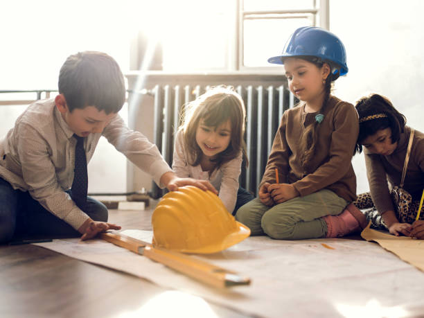 istock Small group of little architects working on blueprints in office. 485684748