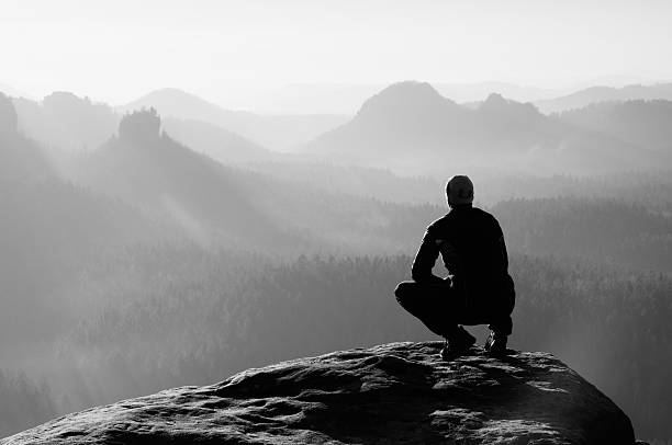 istock Young man in black sportswear is sitting on cliff's edge 485687730