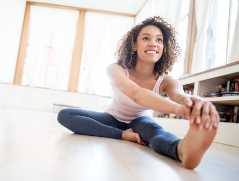 Fit African American young woman stretching at home before her workout - fitness concepts