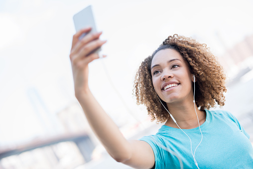 Female runner taking a selfie outdoors with her smartphone while working out