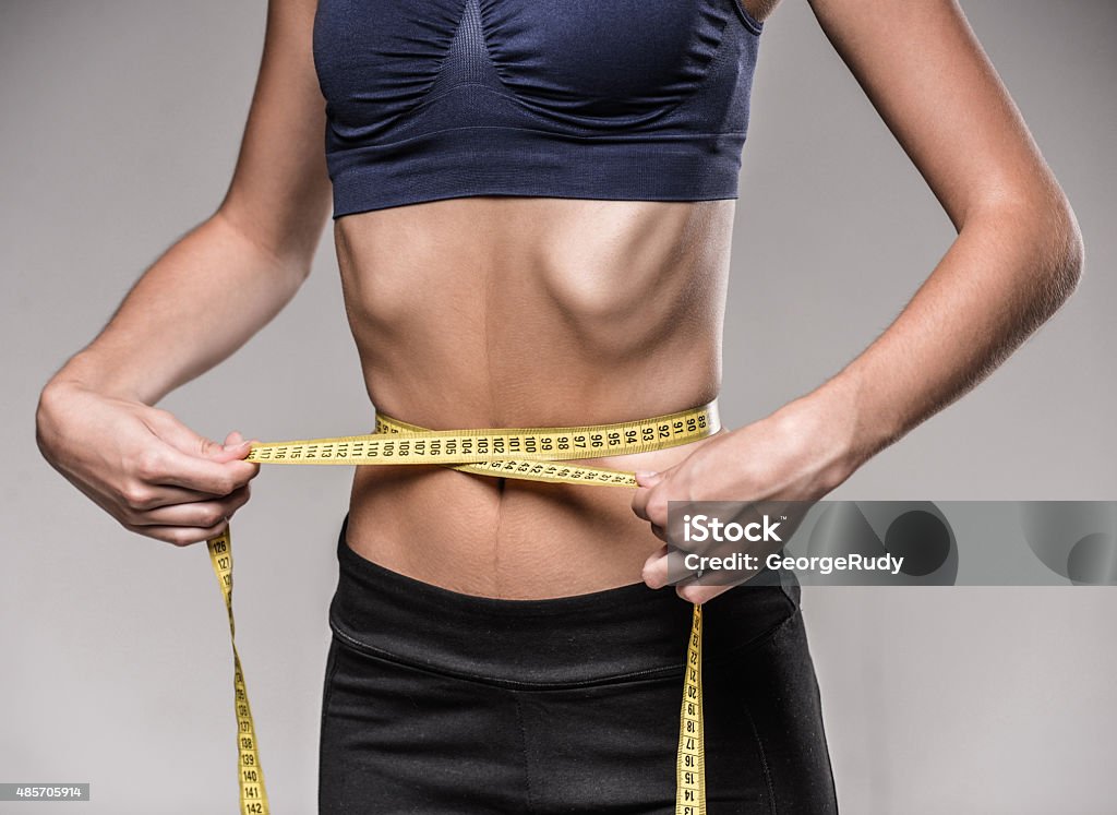 Diet Young skinny woman is measuring her waist during diet. Adult Stock Photo