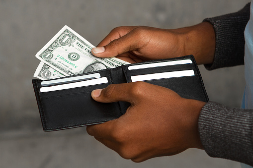 Young African American teen with very little money in his wallet. 