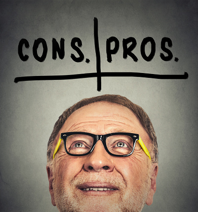 pros and cons, for and against argument concept. Closeup portrait of thinking old man with glasses looking up isolated on gray wall background with copy space