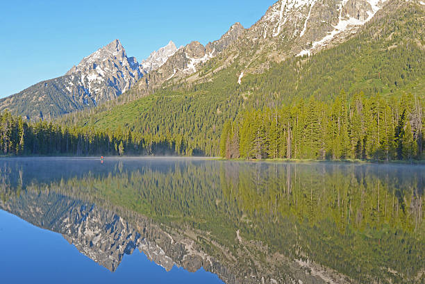 istock Water reflections and fog lay on a clear blue lake. 485713644