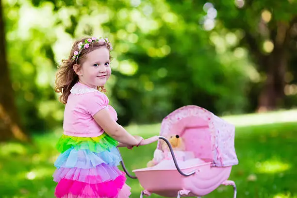 Photo of Little girl pushing a toy stroller wth doll