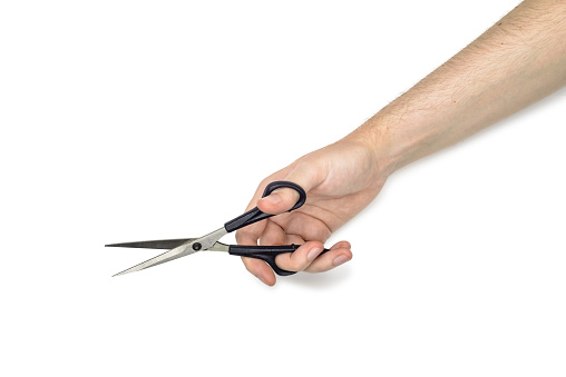 A woman is holding metallic scissors with black handles, isolated on white background