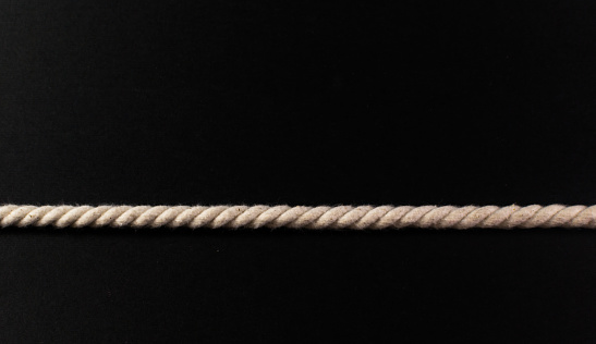 Simple taut strand of white rope on a black background