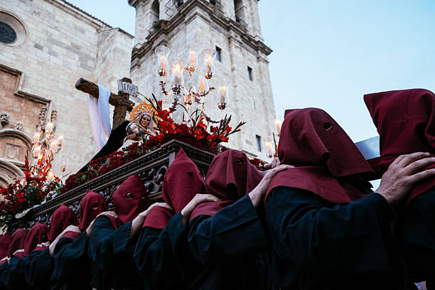 Procession in Spain Alcala de Henares, Spain - April 14, 2014: A group of cofrades wearing a mask hold a statue of Christ and the Virgin Mary during a Holy Week procession. alcala de henares stock pictures, royalty-free photos & images