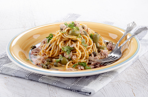 spaghetti with tuna, olive, caper and basil on a plate