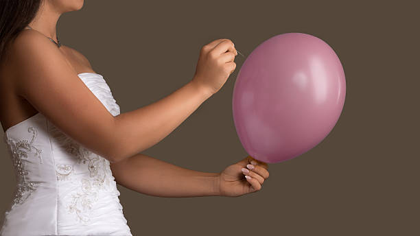 istock Bride in wedding dress lets a Balloon burst with needle 485733104