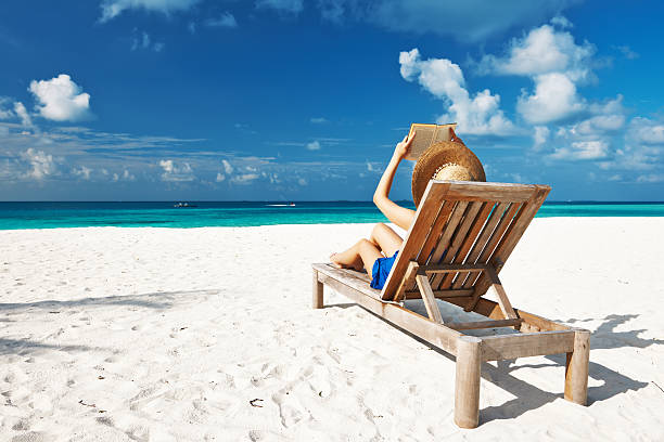 istock Young woman reading a book at beach 485733407