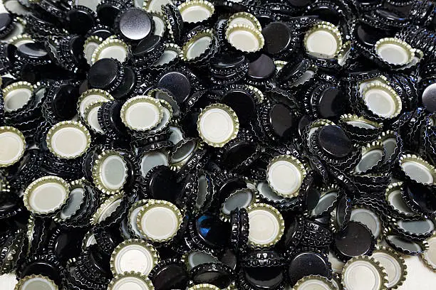 Bottle caps in a bunch shot in an abstract way during the homebrew bottling process.
