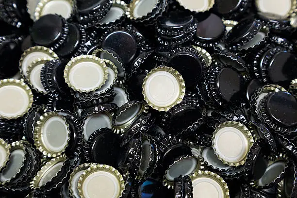 Bottle caps in a bunch shot in an abstract way during the homebrew bottling process.