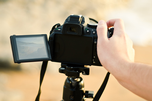 A hand clicking the shoot button of a camera