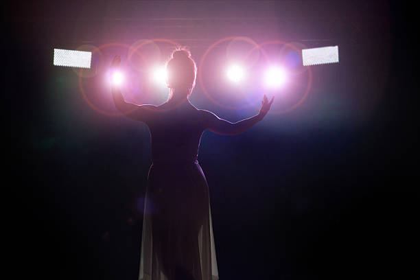 Artist saluting the public Young women artist (singer or classical dancer) is saluting the public. Rear view from backstage with spotlight in camera lense. opera stock pictures, royalty-free photos & images