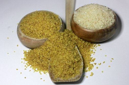 Bulgur and rise  in a wooden spoon and bowl  on white background