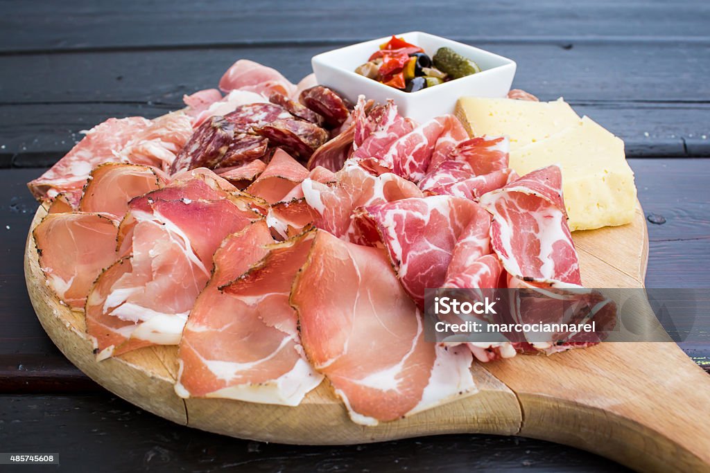 typical Italian appetizer with salami, cheese and pickles typical Italian appetizer with salami, cheese and pickles in a wooden cutting board 2015 Stock Photo