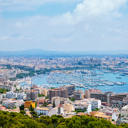 Aerial view of Palma de Majorca - main city in Balearic islands, Spain. Port of Palma Bay and old town taken from the Bellver Castle. Many modern hotels and apartments and mountain at the background