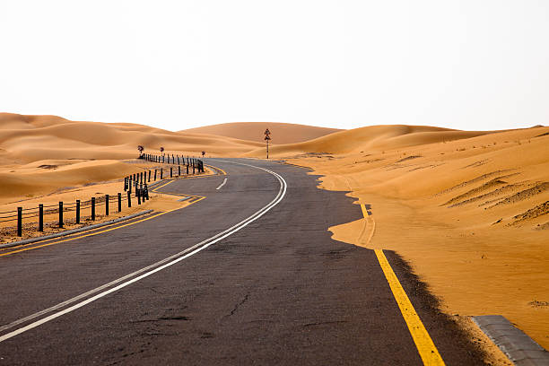 kurvenreiche straße und sanddünen in der liwa, vereinigte arabische emirate - liwa desert stock-fotos und bilder
