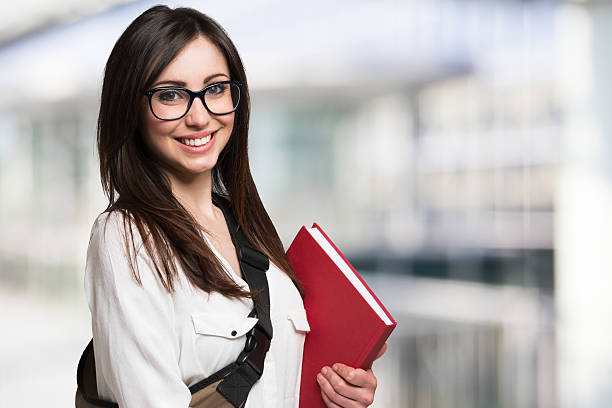 joven mujer sosteniendo un libro - graduation student women beauty fotografías e imágenes de stock