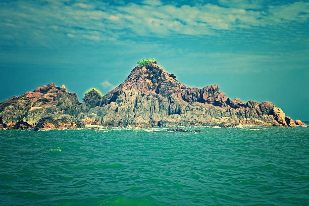Seascape with a rocky island and sky with clouds. India