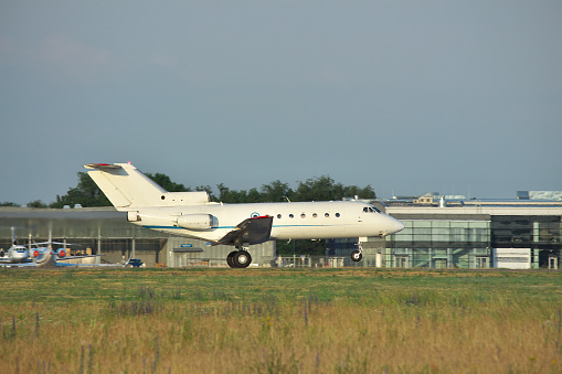Regional or business jet is taking off from the runway in the airport at the end of the day - side view